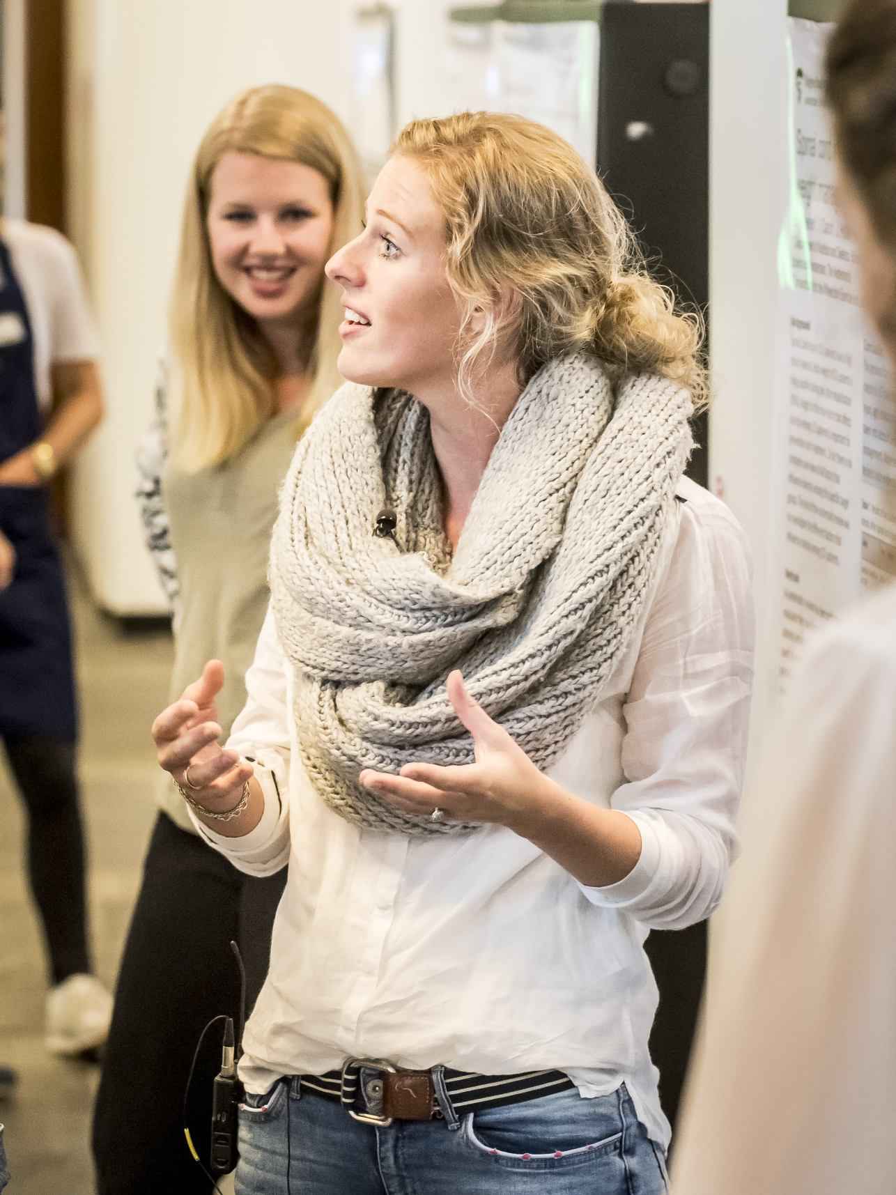 student praat met andere studenten en staat bij een presentatiebord, leergang leefstijlcoach HvA