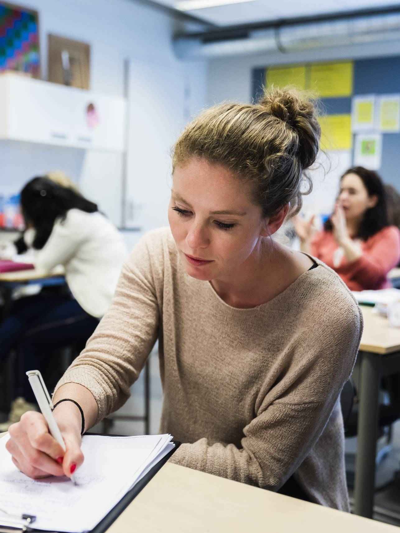 student maakt aantekeningen aan tafel in de klas