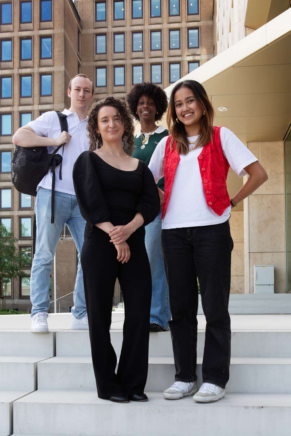 Vier studenten voor een schoolgebouw.