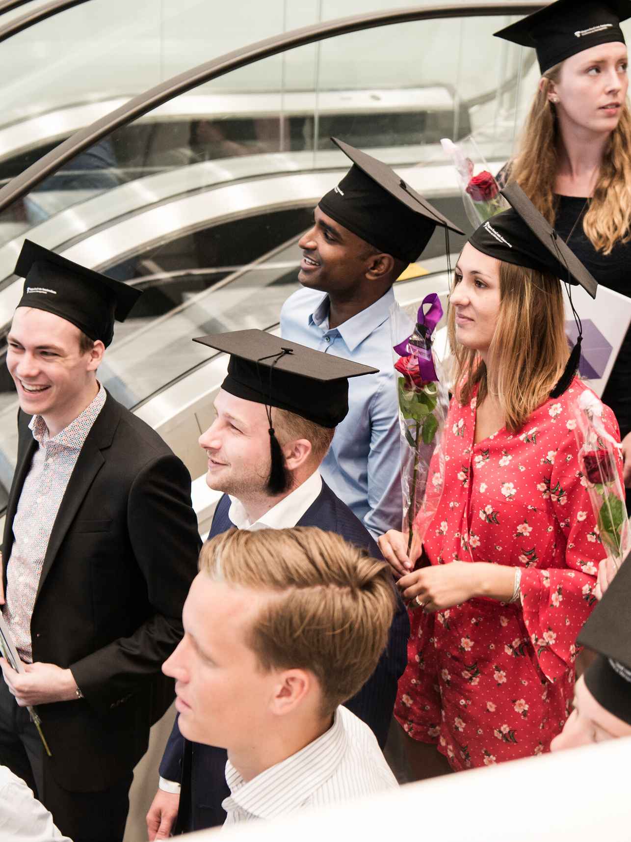 Vier studenten dragen afstudeerbaret.