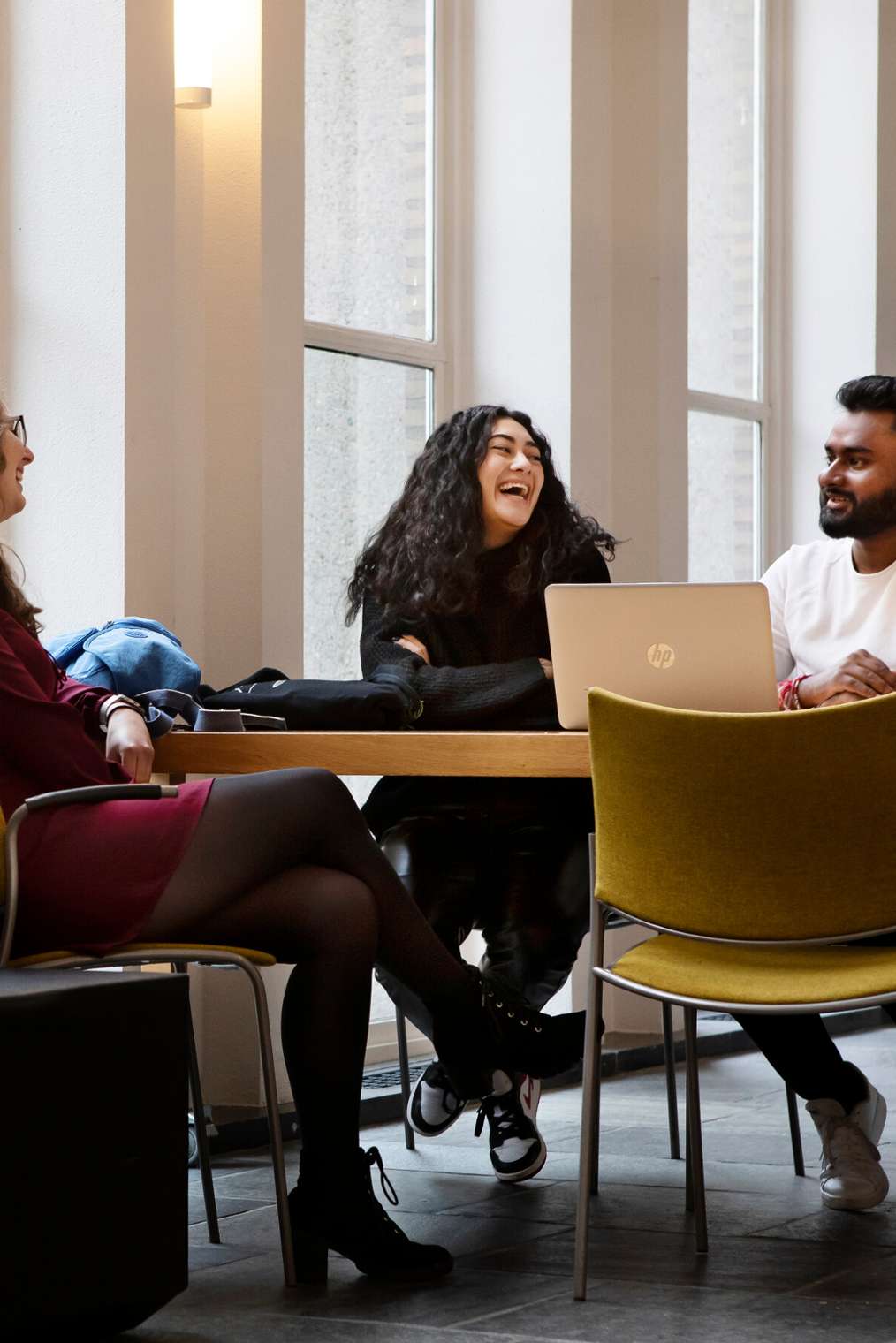 Drie studenten aan tafel met elkaar in gesprek