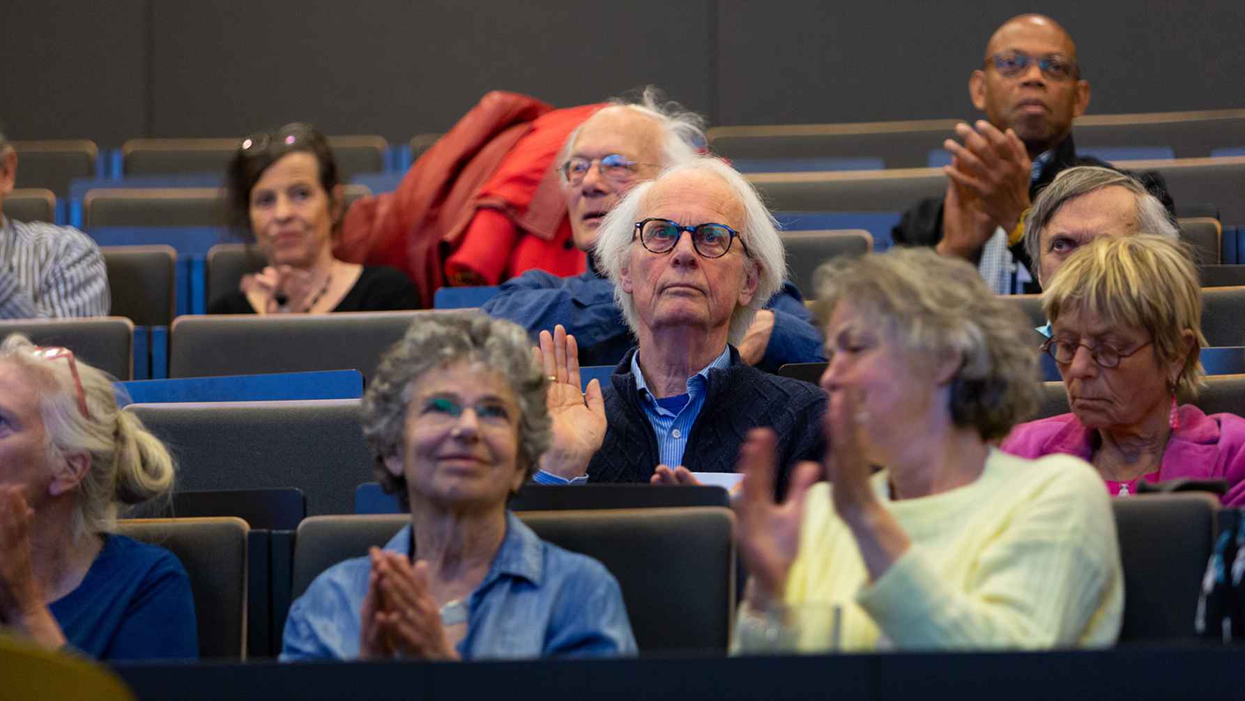een groep oudere werknemers luisteren in een collegezaal naar een spreker