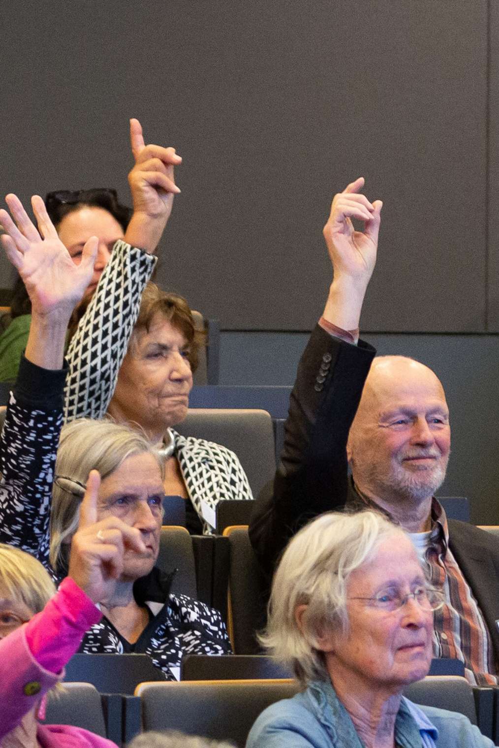 een groep oudere werknemers steken hun vinger op tijdens een lezing
