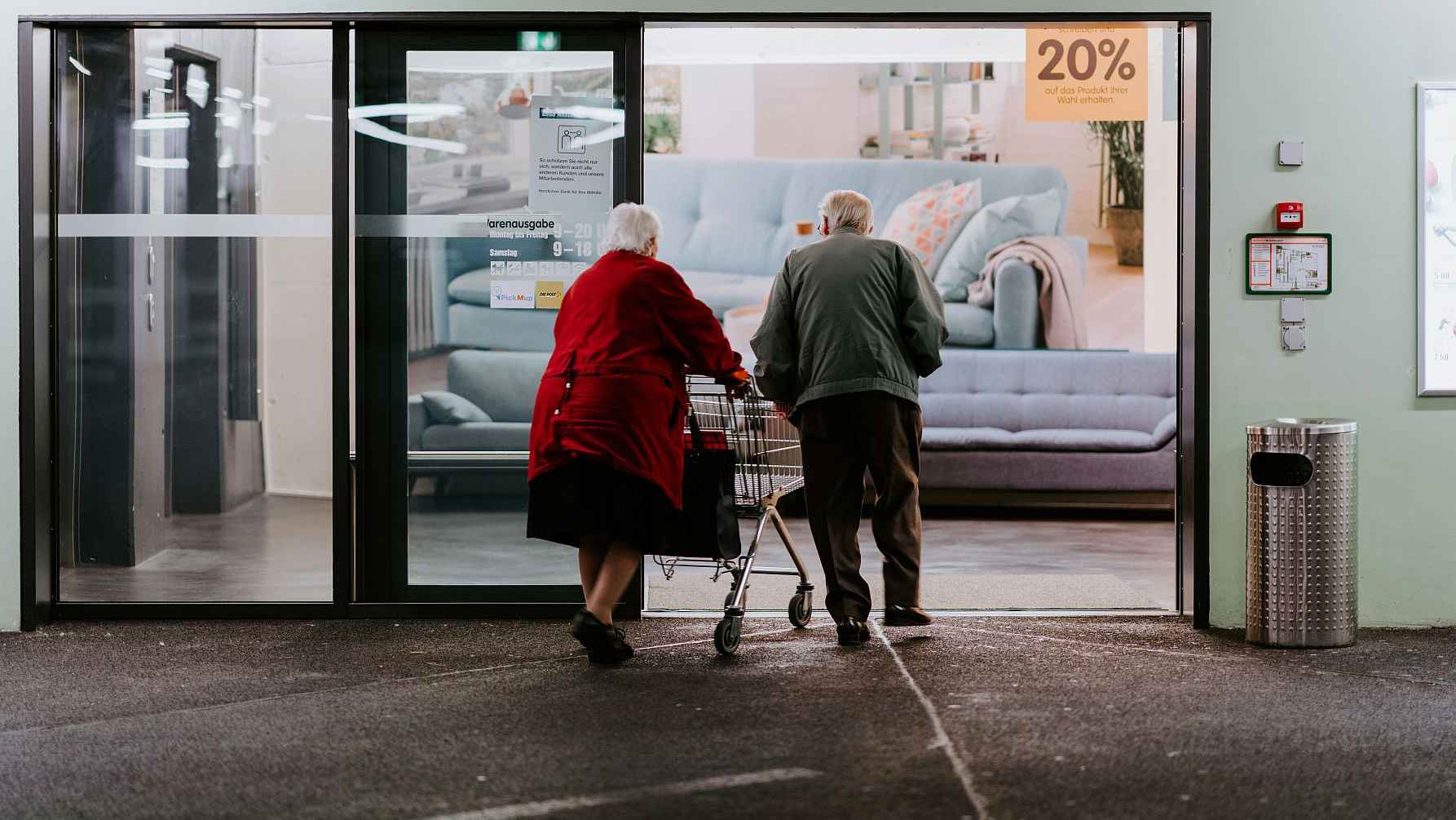 Oudere mensen lopen een winkel in.