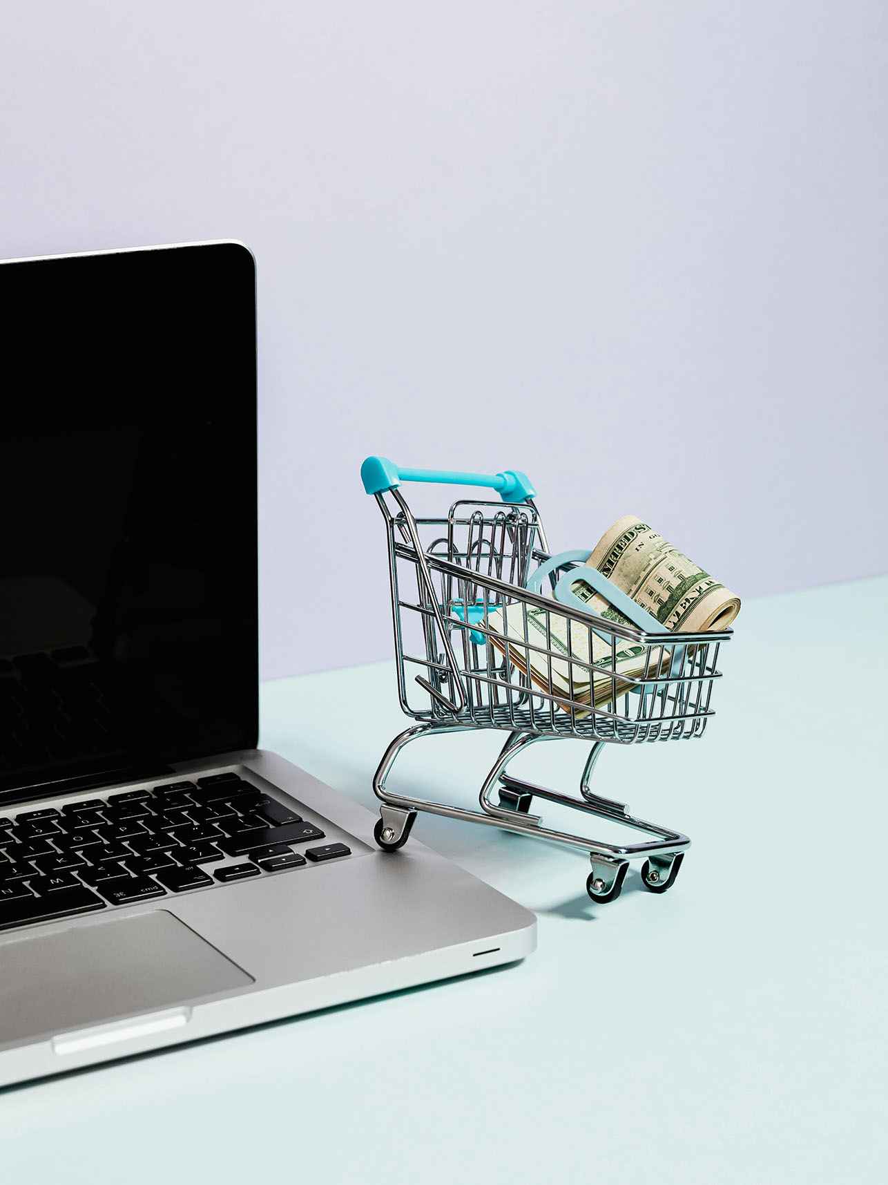 Mini shopping cart next to a laptop.