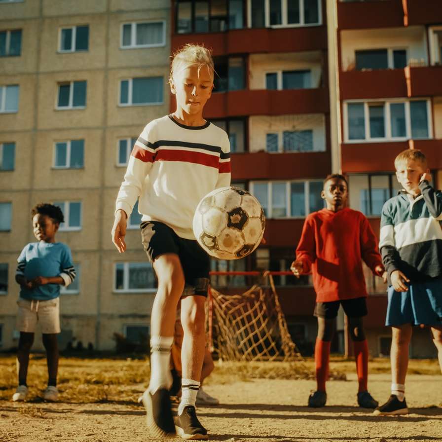 Voetballend meisje tussen jongens