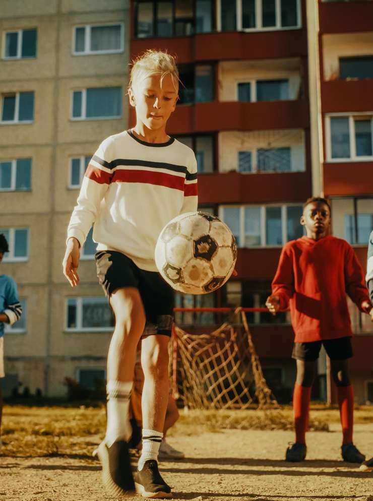 Voetballend meisje tussen jongens
