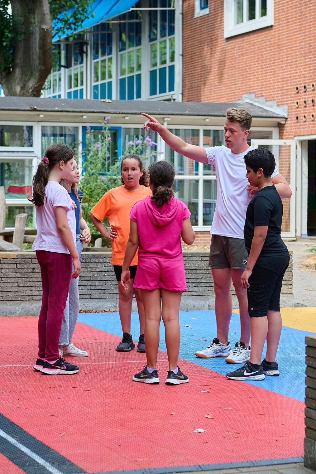 gymdocent staat met groepje basisschoolkinderen op schoolplein, ALO Amsterdam HvA