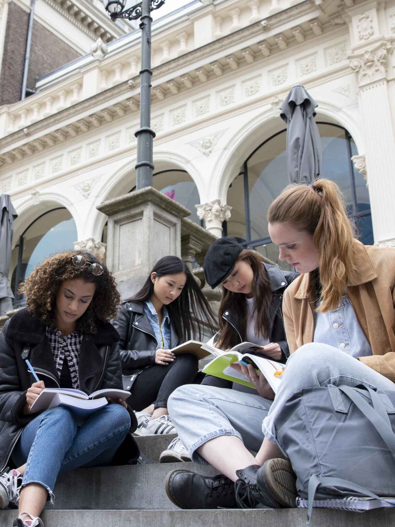 four AMSIB students studying on the steps at Vondelpark