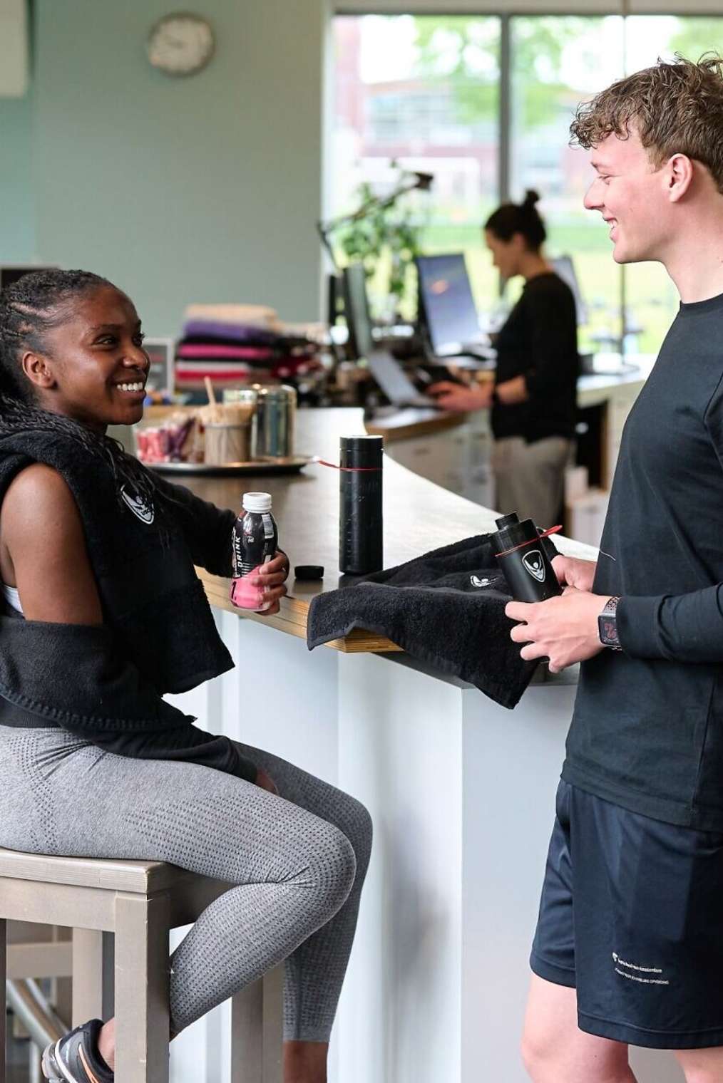 Studenten in sportschool in gesprek bij balie