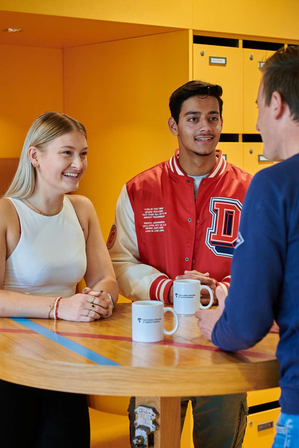Drie studenten aan tafel met elkaar in gesprek
