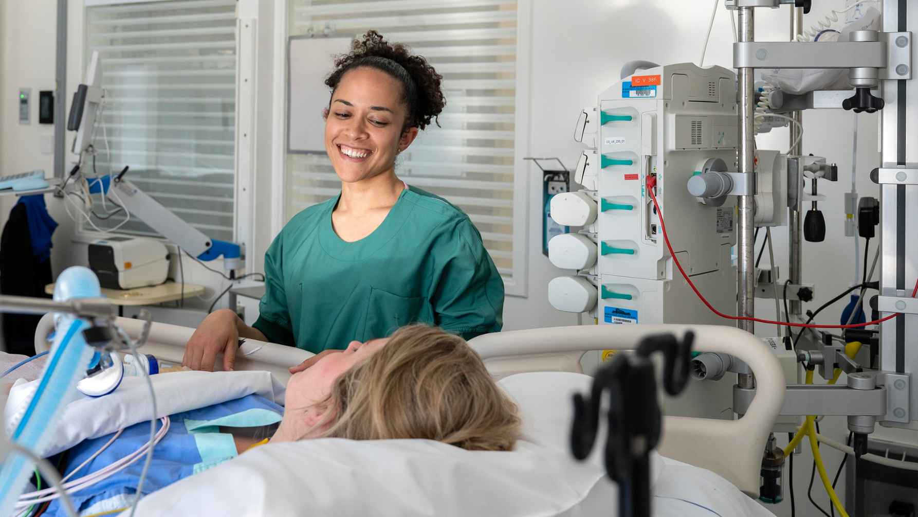 verpleegkundige staat aan bed van ziekenhuispatiënt