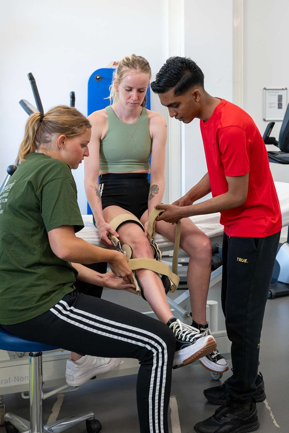 Fysiotherapeut doet kniebrace om bij client met blessure