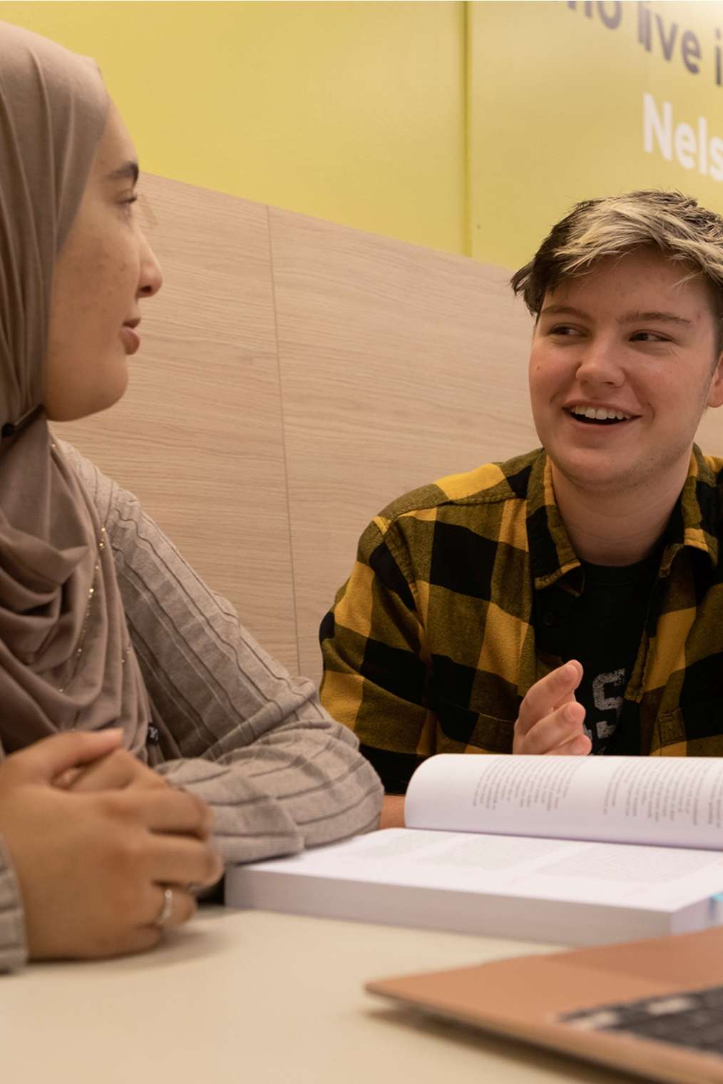 Drie studenten aan tafel met elkaar in gesprek