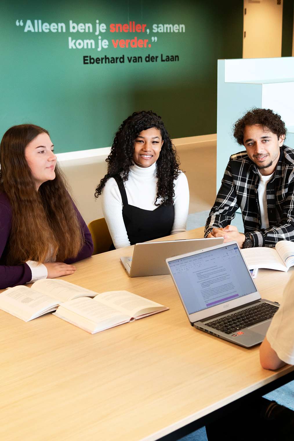 Drie studenten aan tafel met elkaar in gesprek