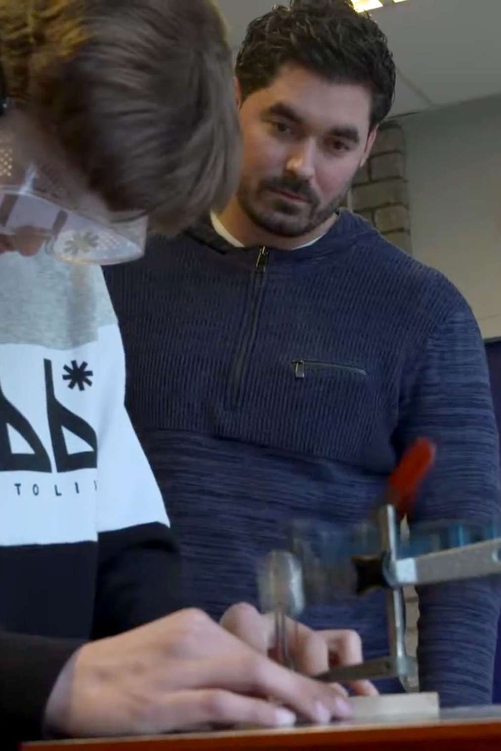 Leerling aan het werk in de werkplaats, leraar kijkt toe
