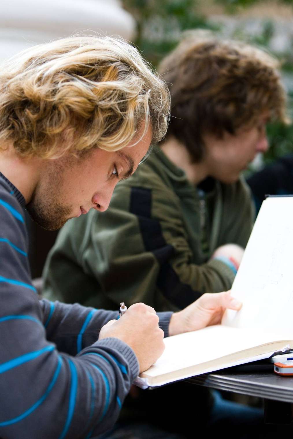 Drie studenten aan tafel met elkaar in gesprek